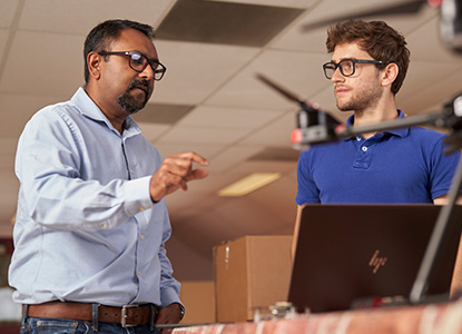 Professor and student discussing a drone as it flies in front of them